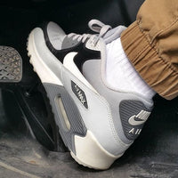 In hand shot van de sneaker met zicht op witte toebox, lichtgrijze mudguard en donkerblauwe Swoosh – mix van materialen in OG-vorm