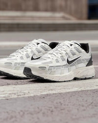 Nike P-6000 Platinum Tint Black gedragen op straat in daglicht, platinum tinten contrasteren met zwarte details, futuristische hardloopstijl gefotografeerd door Snrkickz.