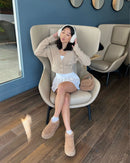 Lifestyle opname van model op houten vloer in loungewear met UGG Plateau Sand aan, vastgelegd in natuurlijke setting
