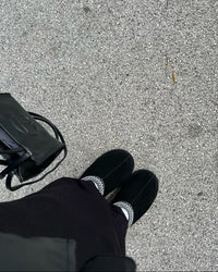 UGG Tazz Slipper Black 1122553-BLK gedragen on-feet in buitenomgeving, zwarte suède slipper met verhoogde zool en opvallende braid detail, vastgelegd door Snrkickz.