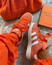 adidas Campus 00s GS ‘Orange Gum’ – close-up van fijne suède textuur, perforaties en de kenmerkende gum outsole in Cloud White accent 