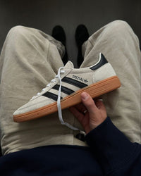 Adidas Handball Spezial Aluminum Core Black – close-up van de Aluminum suède textuur, zwarte leerdetails en goudkleurig Spezial-logo