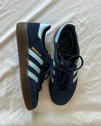 Adidas Handball Spezial Navy Gum – close-up van de navy suède textuur, wit leren details en goudkleurig Spezial-logo