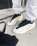 On-foot beeld van de Yeezy Azael gedragen met grijze sweatpants, gefotografeerd op straat met nadruk op glow-cage en futuristisch silhouet