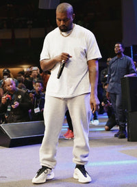 Kanye West on stage in full neutral fit met Yeezy 700 V3 Azael aan, zichtbaar met witte outfit en podiumsetting