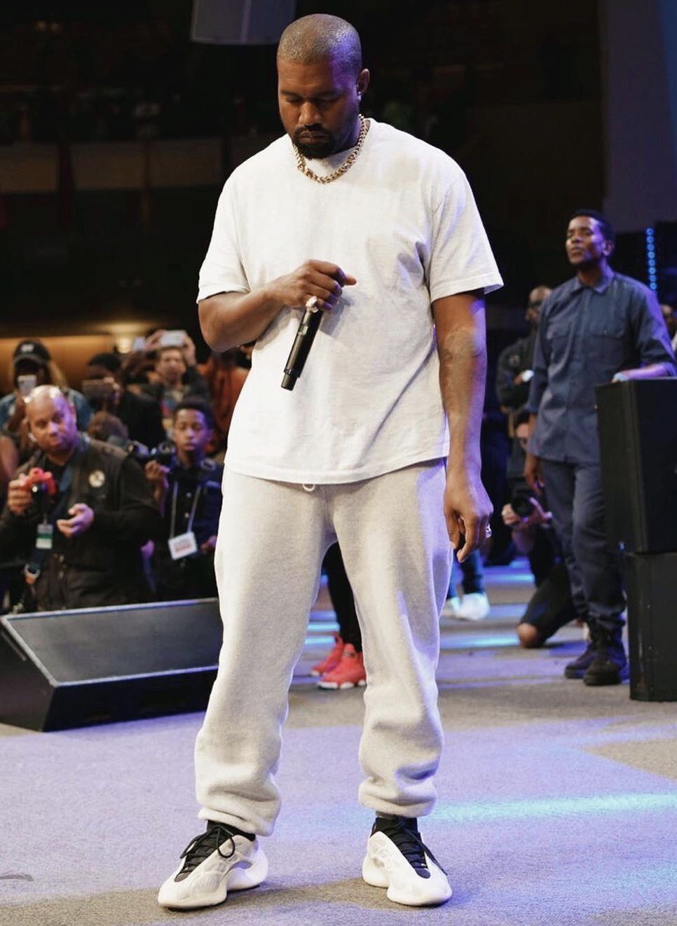 Kanye West on stage in full neutral fit met Yeezy 700 V3 Azael aan, zichtbaar met witte outfit en podiumsetting