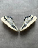 Flatlay van twee Yeezy 700 V3 Fade Salt sneakers op betonnen ondergrond, met zicht op futuristische cage en vetersysteem