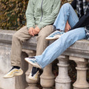 On-foot beeld van de Yeezy 700 Kyanite gedragen met jeans en earth-tone outfit, zittend op balustrade in stadse omgeving