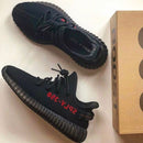 Adidas Yeezy Boost 350 V2 Black Red CP9652 als paar naast elkaar met originele doos, gefotografeerd op lichte achtergrond