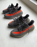 Adidas Yeezy Boost 350 V2 Carbon Beluga HQ7045 als paar naast elkaar gefotografeerd, met focus op de grijze en oranje colorway