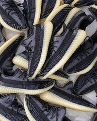 Meerdere paren Adidas Yeezy Boost 350 V2 Carbon FZ5000 gestyled bij elkaar, met zichtbare knit textuur en lichtgekleurde zool