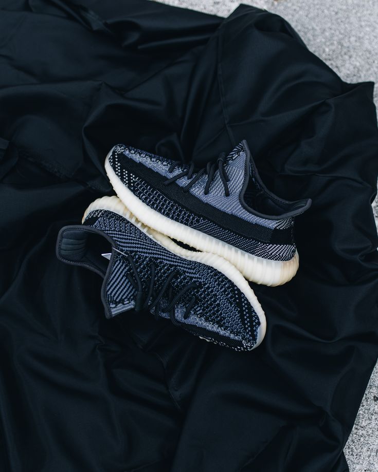 Adidas Yeezy Boost 350 V2 Carbon FZ5000 gefotografeerd op donkere stof, waarbij de zwarte Primeknit en lichte zool contrasteren