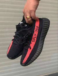 Adidas Yeezy Boost 350 V2 Core Black Red BY9612 vastgehouden met zicht op de rode zijstreep en Primeknit textuur