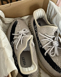 Adidas Yeezy Boost 350 V2 Slate HP7870 gefotografeerd met de originele Yeezy doos, waarbij de beige knit en zwarte zijstreep duidelijk zichtbaar zijn