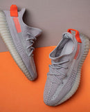 Adidas Yeezy Boost 350 V2 Tail Light FX9017 van bovenaf gefotografeerd op oranje achtergrond, met focus op het felle hielaccent