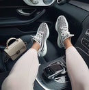 Adidas Yeezy Boost 350 V2 Zebra CP9654 gedragen in een auto-interieur, waarbij de opvallende strepen en rode branding zichtbaar zijn