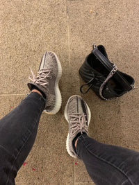 Adidas Yeezy Boost 350 V2 Zyon FZ1267 gedragen met donkere broek in een casual setting, gefotografeerd samen met een tas