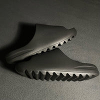 Meerdere Yeezy Slide Onyx HQ6448 paren in display – stacked opstelling met matte afwerking en urban streetwear vibe