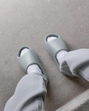 Yeezy Slide Salt aan voet met witte sokken – cleane zomervibe voor airport fits, festivals of loungewear