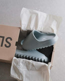 Uit de doos: Yeezy Slide Salt – zachte EVA-structuur met robuuste ribbelzool en Yeezy-merk binnenin zichtbaar
