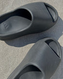 Yeezy Slide Slate Marine ID2349 aan voet met beige sokken – stijlvolle donkere slipperlook voor zomer of airport fits