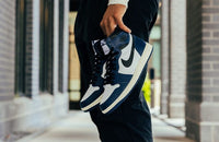 Flatlay van de sneaker met bijbehorende navy Nike-box – benadrukt het minimalistische en tijdloze karakter van deze retro-release


