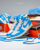 Meerdere paren van de Air Jordan 1 UNC Reimagined naast OG-doos – iconisch Jordan silhouet in University Blue met contrasterende crèmekleurige zool
