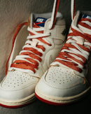 Topview van de Air Jordan 1 Cinnabar met zalmrode veters en geperforeerde toebox – mix van lichte tinten en OG details in vernieuwde uitvoering