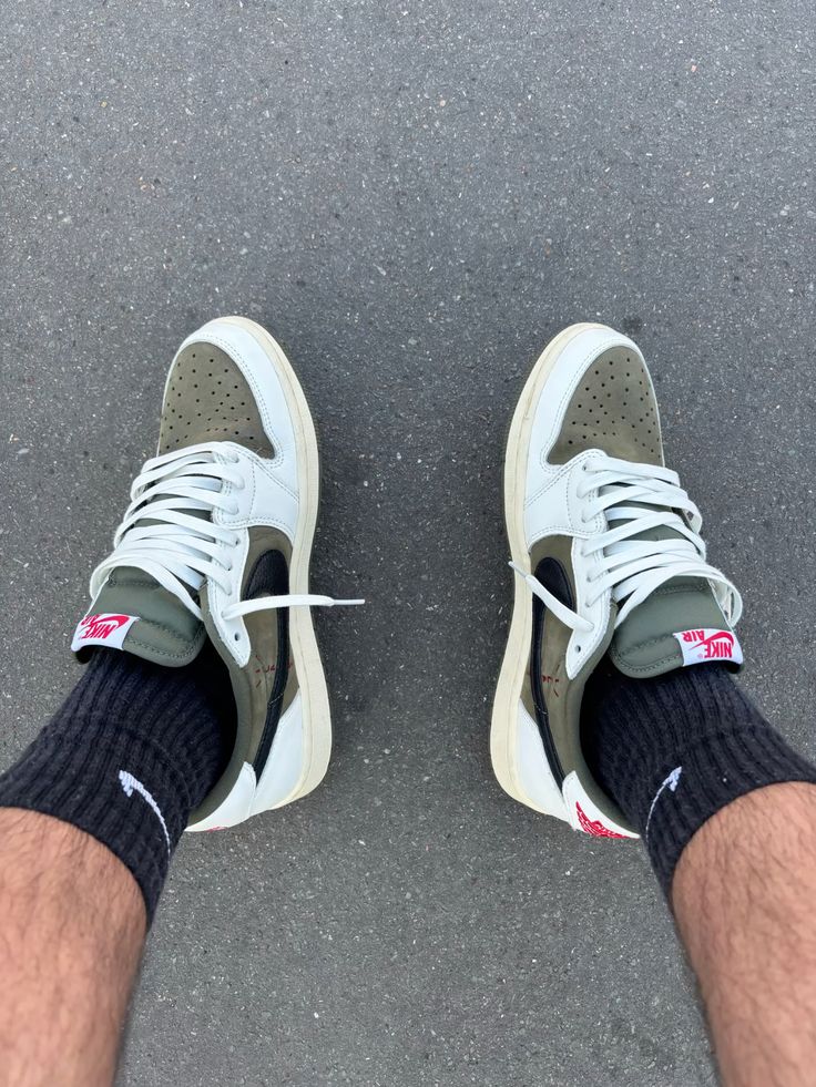 Air Jordan 1 Low OG Travis Scott Medium Olive (SKU DM7866‑200) – in‑hand shot met zicht op reversed Swoosh, Cactus Jack heel-logo en olive rubber outsole