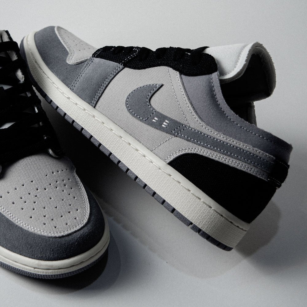 Detail van Air Jordan 1 Low SE Craft Inside Out Cement Grey (SKU DZ4135‑002) met cement grey suede Swoosh en exposed stitching