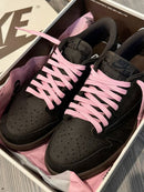 Air Jordan 1 Low OG Travis Scott Velvet Brown (SKU DM7866‑202) – in‑hand shot met zicht op reverse Swoosh, woven Nike Air tag en brown rubber outsole