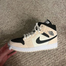 Close‑up Air Jordan 1 Mid Barely Orange – focus op zwarte Wings-logo, stitching en leertextuur voor legit checks en materiaalbewuste kopers