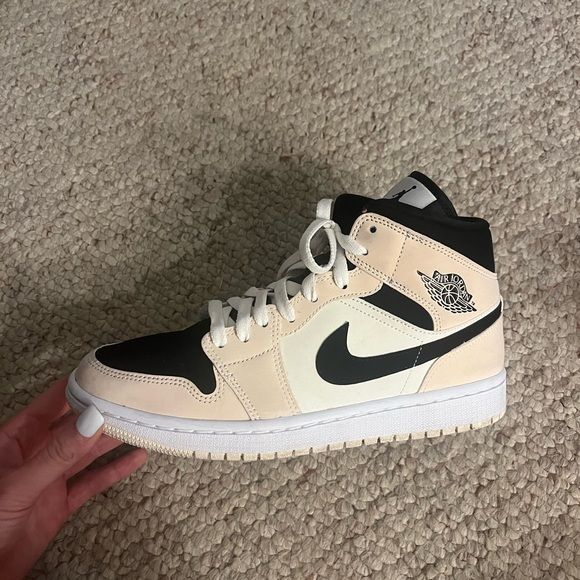 Close‑up Air Jordan 1 Mid Barely Orange – focus op zwarte Wings-logo, stitching en leertextuur voor legit checks en materiaalbewuste kopers