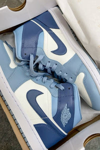 In-hand shot Jordan 1 Mid Diffused Blue – helder blauw leer, witte zool en lichtgrijze accenten zichtbaar onder natuurlijk licht