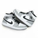 Uit de doos: Air Jordan 1 Mid Light Smoke Grey – zicht op zool, tonglabel en de kleurverdeling van grijs, wit en zwart leer