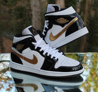 Close-up Air Jordan 1 Mid Patent Black White Gold – focus op glossy patent leer, goudkleurig Wings-logo en stitching; top voor legit check visuals