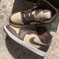 Jordan 1 Mid SE Paris YMCA in hand – marineblauwe Swoosh, witte zool en grijze overlays goed zichtbaar in natuurlijk licht