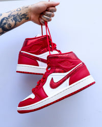 Air Jordan 1 Mid SE Red Cracked Leather – close‑up van gescheurd metallic leer op Swoosh en kraag voor Y2K finish