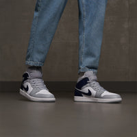 AJ1 Mid Wolf Grey Midnight Navy on‑feet – gedragen met lichtgrijze cargopants; urban street-style look die geliefd is onder Gen Z sneakerfans