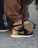 On feet shot van de Jordan 1 Black Metallic Gold met wijde broek