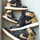 Twee paar Jordan 1 Black Metallic Gold op elkaar gestapeld in grote en kleine maten i