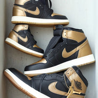 Twee paar Jordan 1 Black Metallic Gold op elkaar gestapeld in grote en kleine maten i