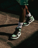 On feet look van de Lucky Green Jordan 1 gecombineerd met zwarte jeans – de groene accenten geven het paar een sportieve, opvallende uitstraling

