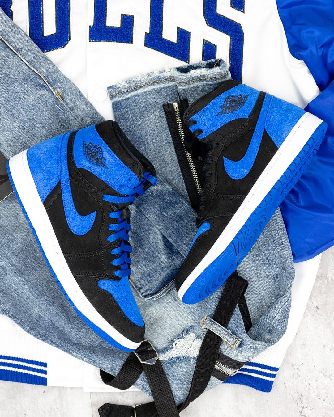 Flatlay van de Royal Reimagined Jordan 1 naast een Bulls-shirt – perfecte match voor een klassieke Chicago-basketballlook in blauw-zwart