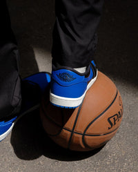 Air Jordan 1 Retro Low ’85 Royal (SKU IB1981‑004) on‑foot met donkere denim, aged midsole en blauwe rubberen outsole