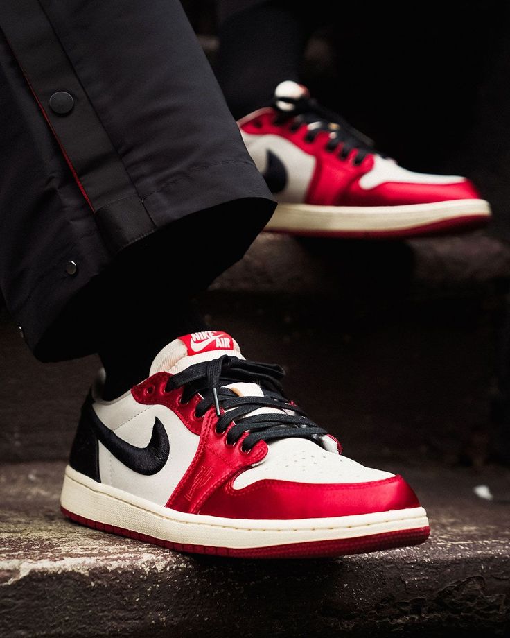 n-hand close-up van de Air Jordan 1 Retro Low OG Chicago 2025 HQ6998-600 met zichtbare stiksels, rode leren afwerking en retro Summit White zool, exclusief bij Snrkickz.