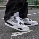 Military Black DH6927-111 gedragen met tapered black pants, gefotografeerd in beweging met focus op de zwart-witte midsole en neutrale styling