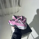 Jordan 4 Orchid AQ9129-501 in één hand vastgehouden met zicht op hielbranding, cementzool en paars lederen structuur