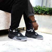 Air Jordan 4 Retro Fear aan voet casual gecombineerd met zwarte broek, exclusieve en donkere Jordan look