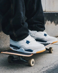 Air Jordan 4 Retro Navy x Nike SB on foot gedragen met zwarte broek, gum zool zichtbaar